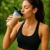 Woman drinking from a protein shake container outdoors